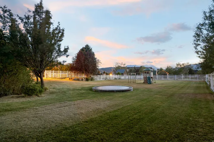 Expansive fenced yard featuring mature trees and mountain scenery