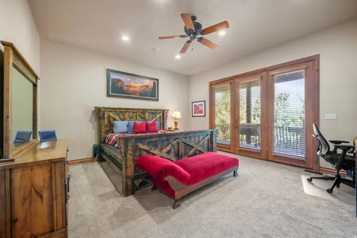 Vaulted ceiling with recessed lighting and a ceiling fan, carpeted flooring, and wood-framed glass doors