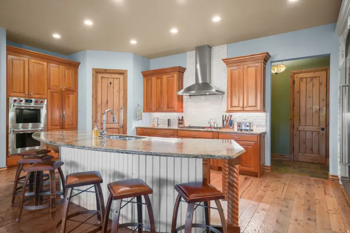 Kitchen featuring wood-finish flooring, recessed lighting, and a center island with a built-in sink