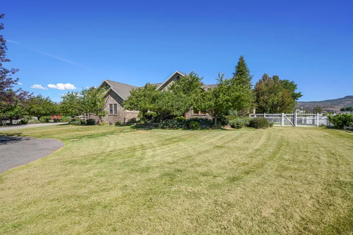 Expansive green lawn with mature trees and a white picket fence
