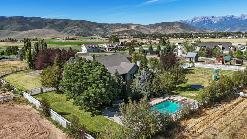 Expansive property featuring a fenced swimming pool, extensive landscaping, and a surrounding white picket fence