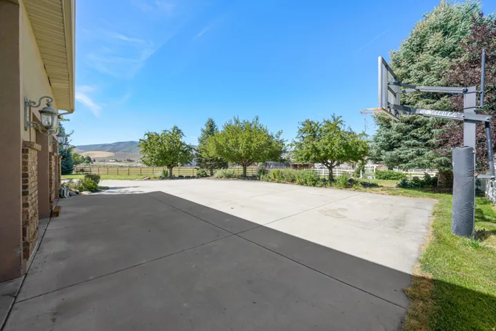 Expansive concrete driveway and patio area, featuring a basketball hoop