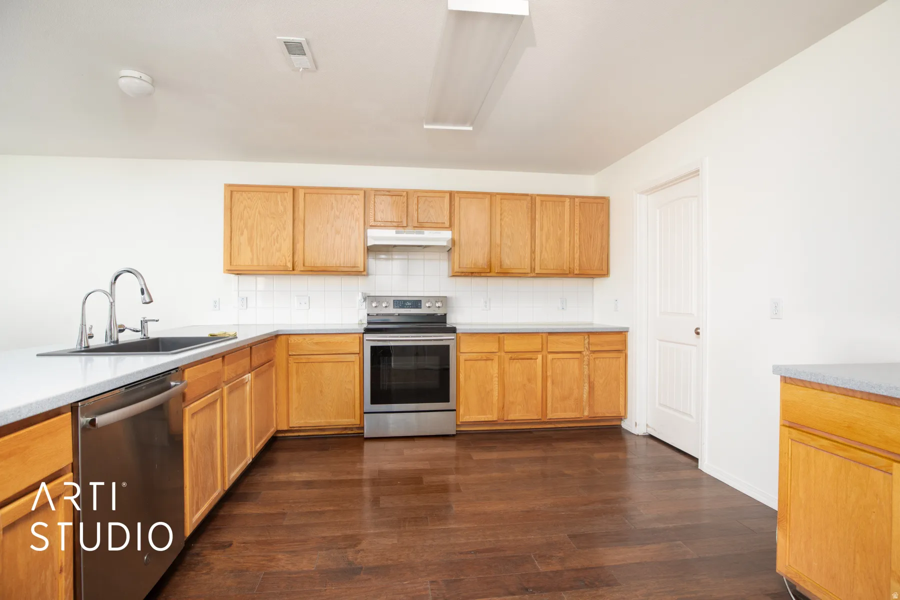 Kitchen featuring wood-finish cabinetry, stainless steel appliances, white subway tile backsplash, and dark wood-finish flooring
