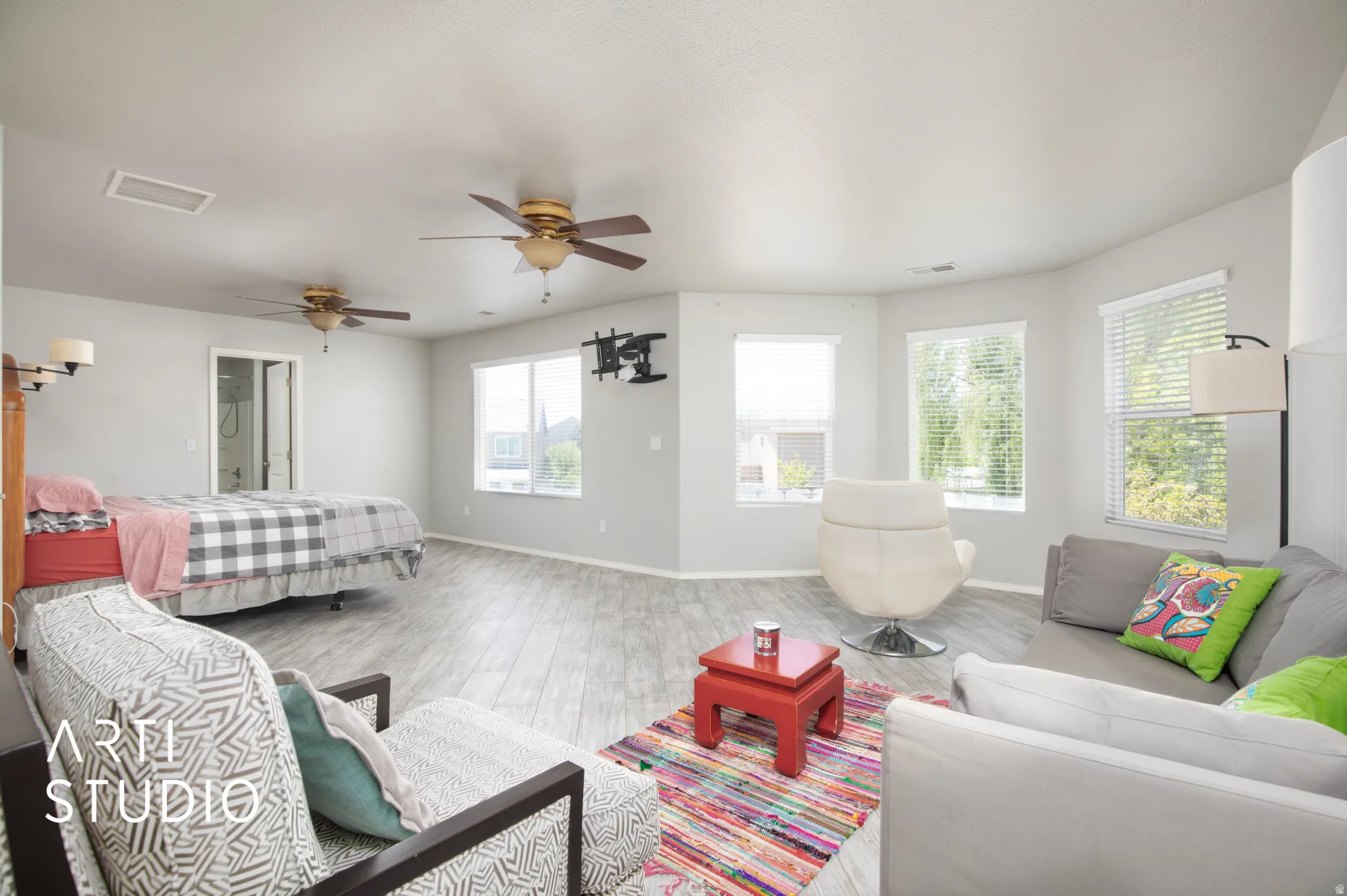 Spacious interior featuring wood-finish flooring, multiple windows with blinds, and two ceiling fans