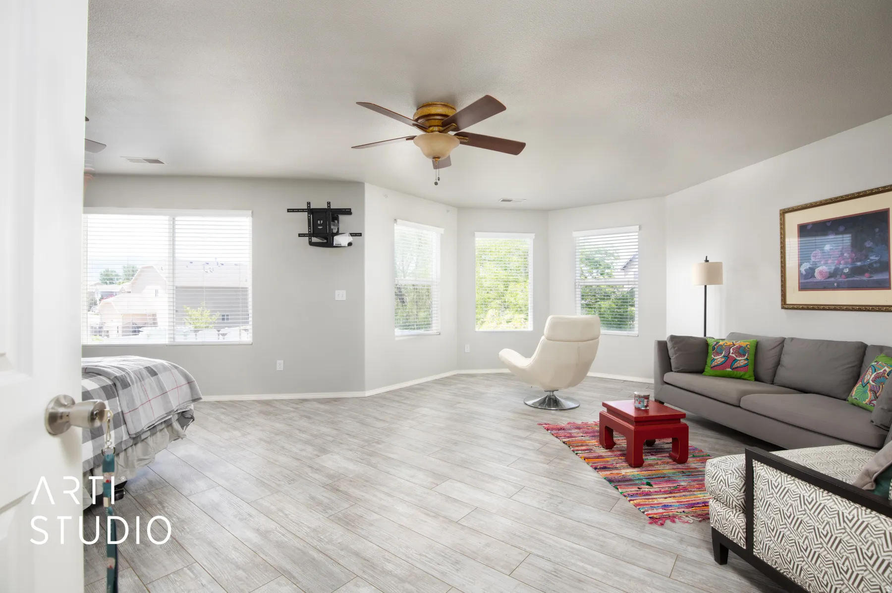 Spacious room featuring wood-finish flooring, multiple windows, and two ceiling fans