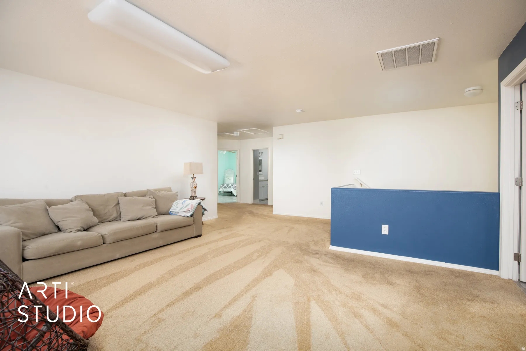 Spacious carpeted room with white walls and a blue accent wall