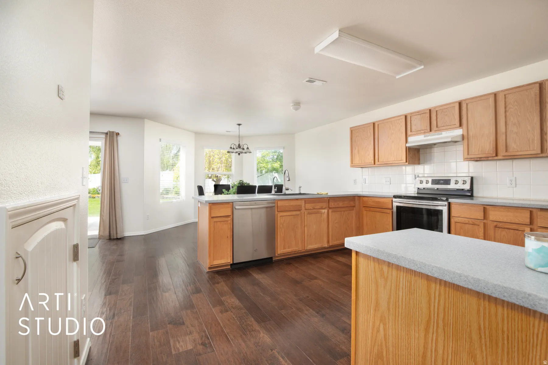 Spacious kitchen featuring warm wood cabinetry, stainless steel appliances, and a large center island with quartz countertop