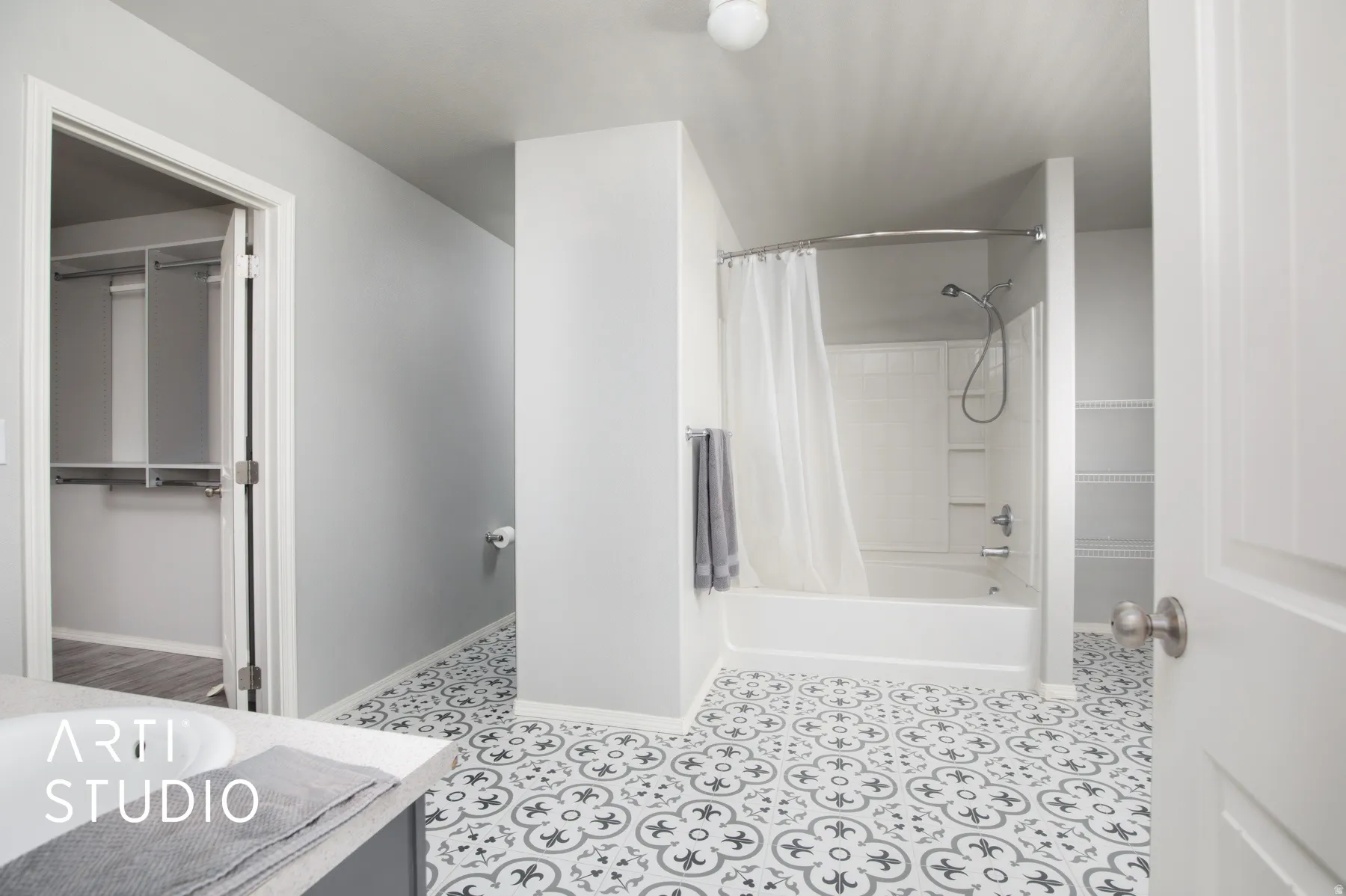 Bathroom featuring patterned floor tiling, a white bathtub with a shower, and an integrated vanity sink with a light-colored countertop