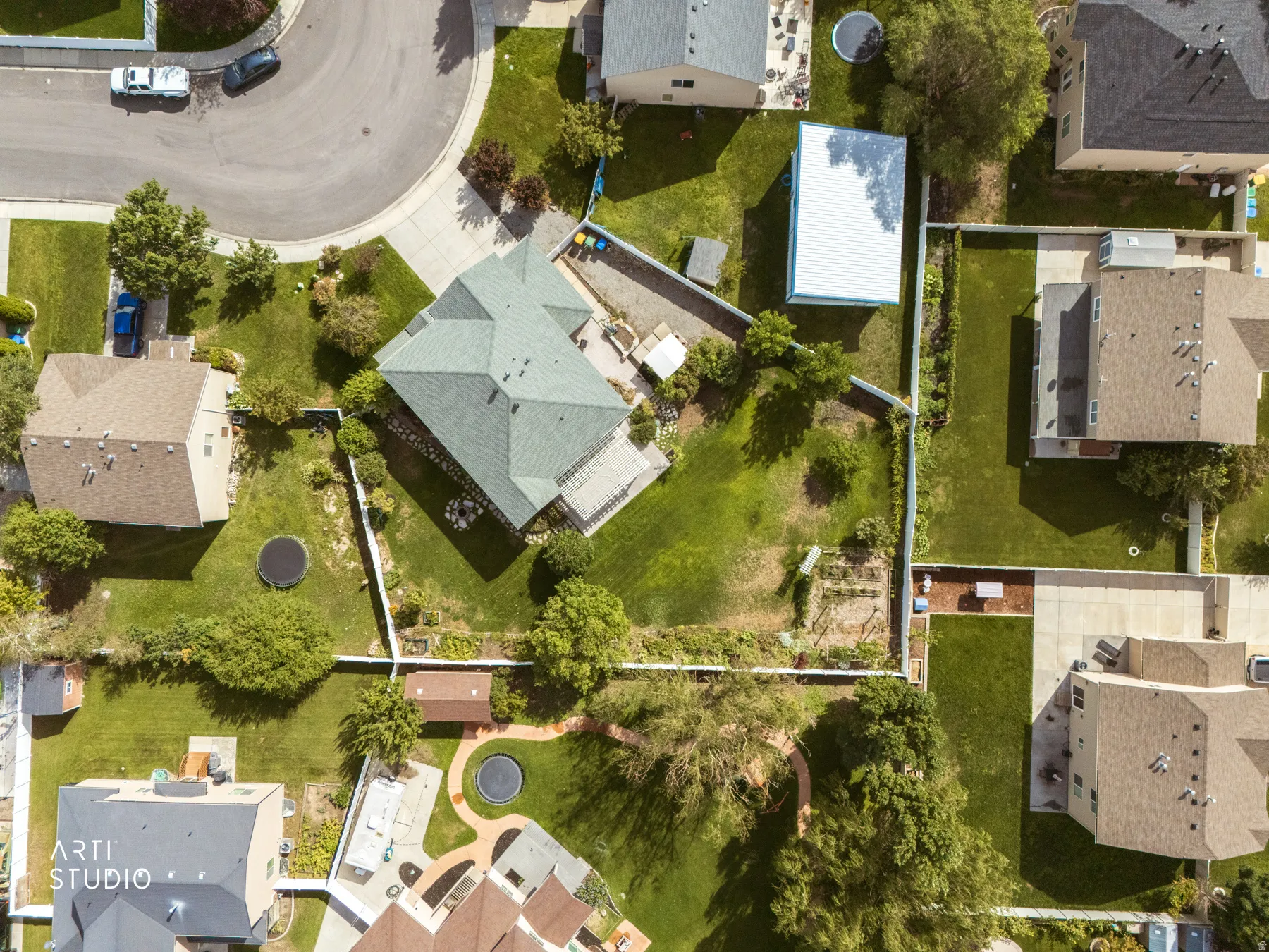 Expansive lot featuring a large residential structure with a green shingle roof, mature landscaping, and a fenced perimeter