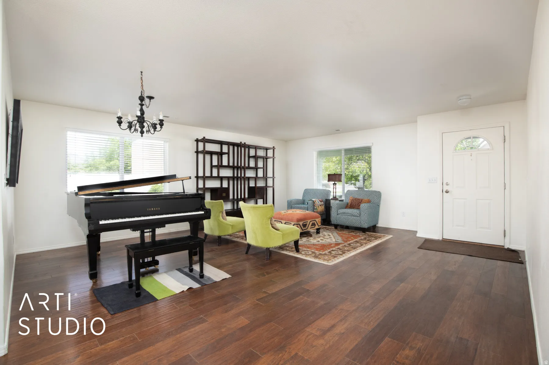 Expansive interior featuring wood-finish flooring, a white paneled entry door with an arched glass insert, large windows, and a built-in shelving unit