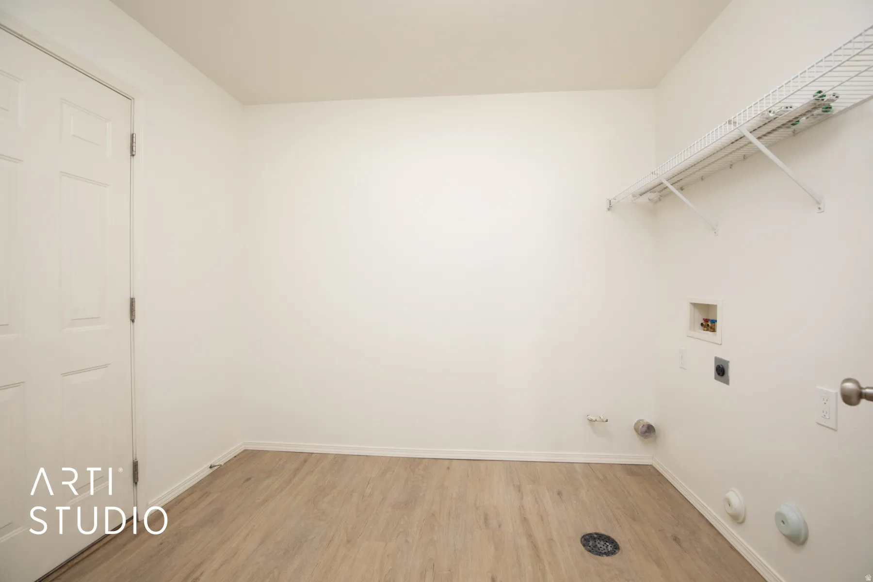 Wood-finish flooring with white baseboards, white walls, and a white paneled door