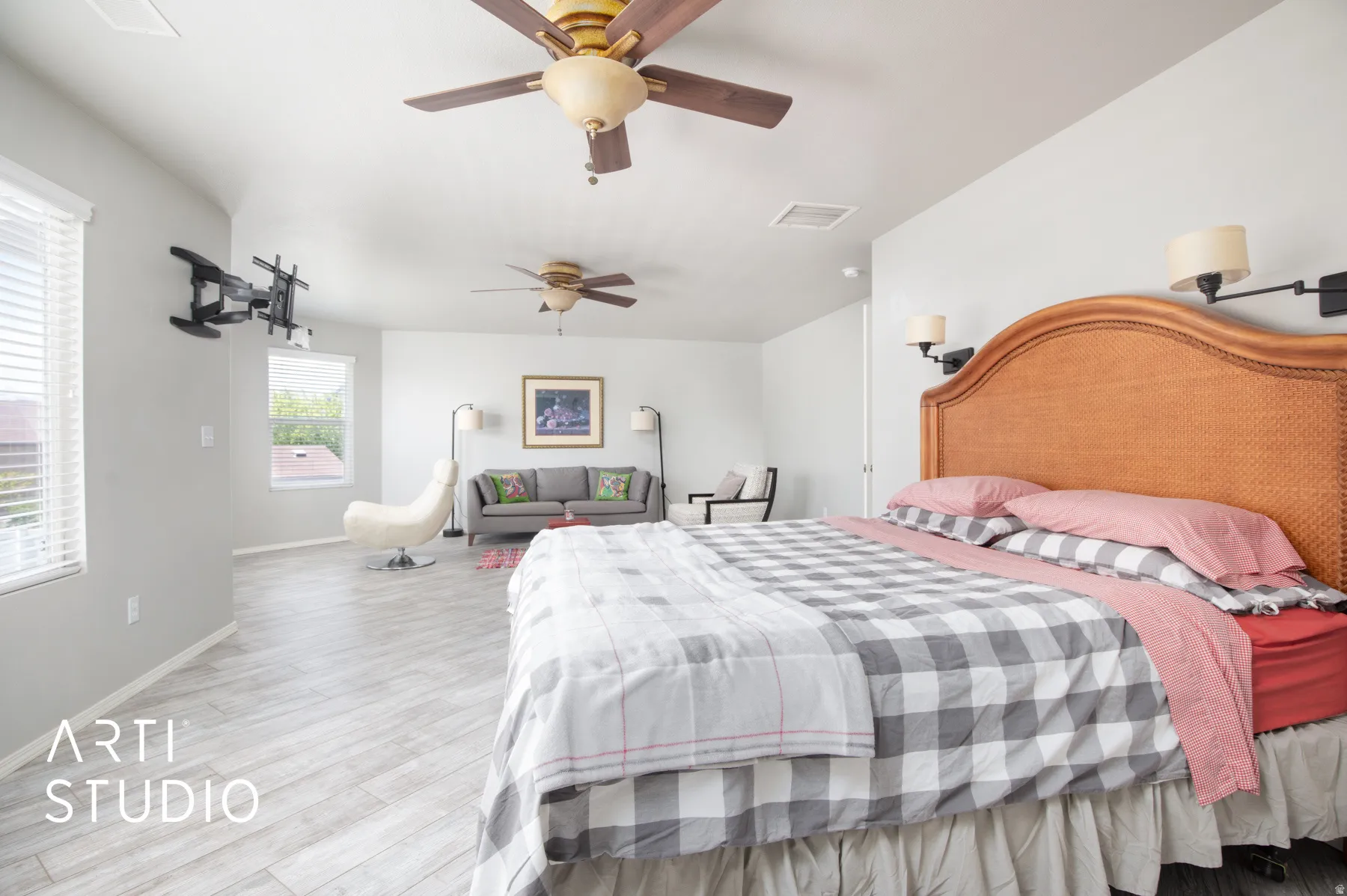 Spacious room featuring wood-finish flooring, two ceiling fans, and two wall sconces
