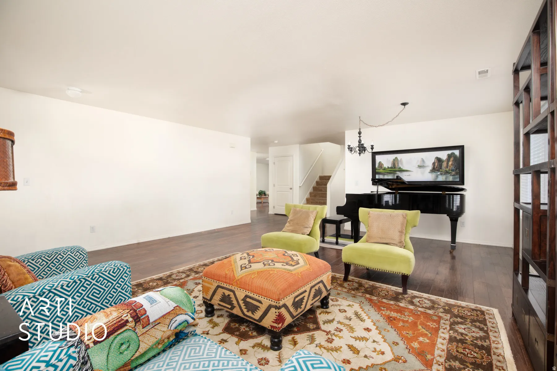 Hardwood-style flooring throughout, staircase with white risers, and a built-in dark wood shelving unit