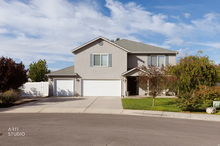 Two-story stucco exterior with a multi-car garage, mature landscaping, and a fenced side yard