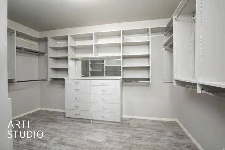 Walk-in closet featuring built-in shelving, hanging rods, an integrated dresser, and a reflective panel