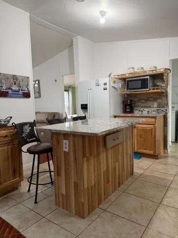 Kitchen featuring a central island with wood paneling and a light-toned countertop, tile flooring, and wood-finish cabinetry