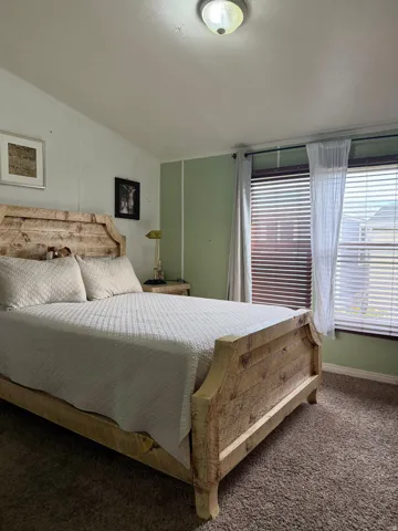 Carpeted flooring, window with blinds and sheer curtains, and a flush-mount ceiling light