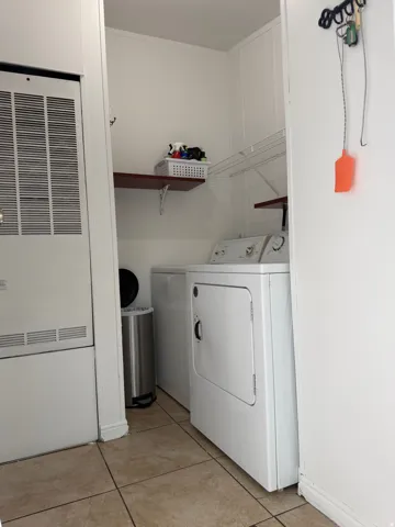 Laundry area with tiled flooring, white walls, and built-in shelving