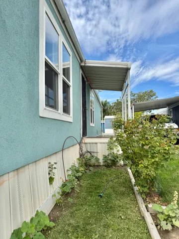 Exterior featuring light blue siding, white trim windows, a covered entry, and a covered carport structure