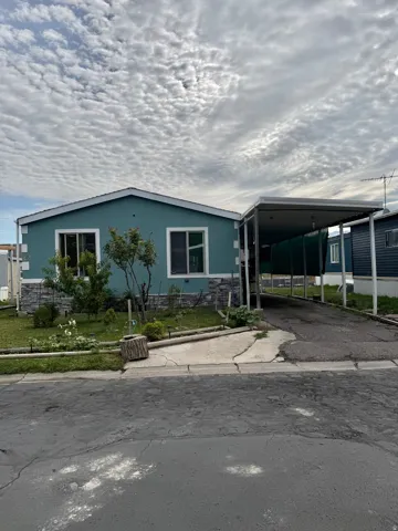 Single-story residence featuring a teal exterior with white trim, a gabled roof, and stone-finish wainscoting