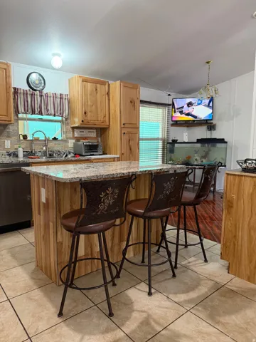 Kitchen featuring a central island with a granite countertop, wood-finish cabinetry, and a tile backsplash