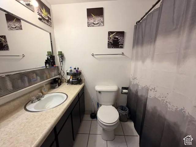 Vanity with a single basin sink, extensive countertop space, and dark cabinetry