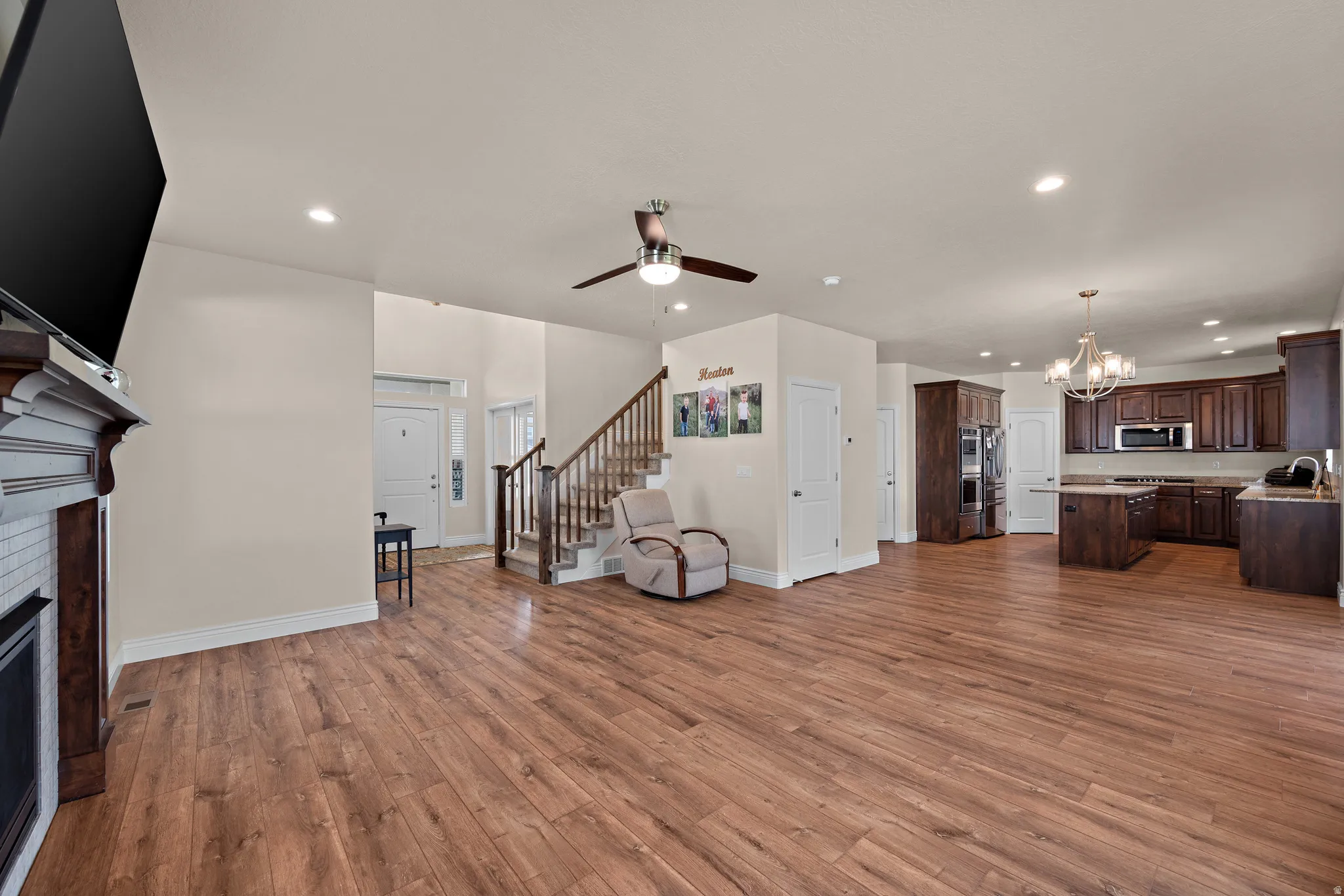 Spacious living area featuring wood-finish flooring, a fireplace with a white tile surround, and a ceiling fan