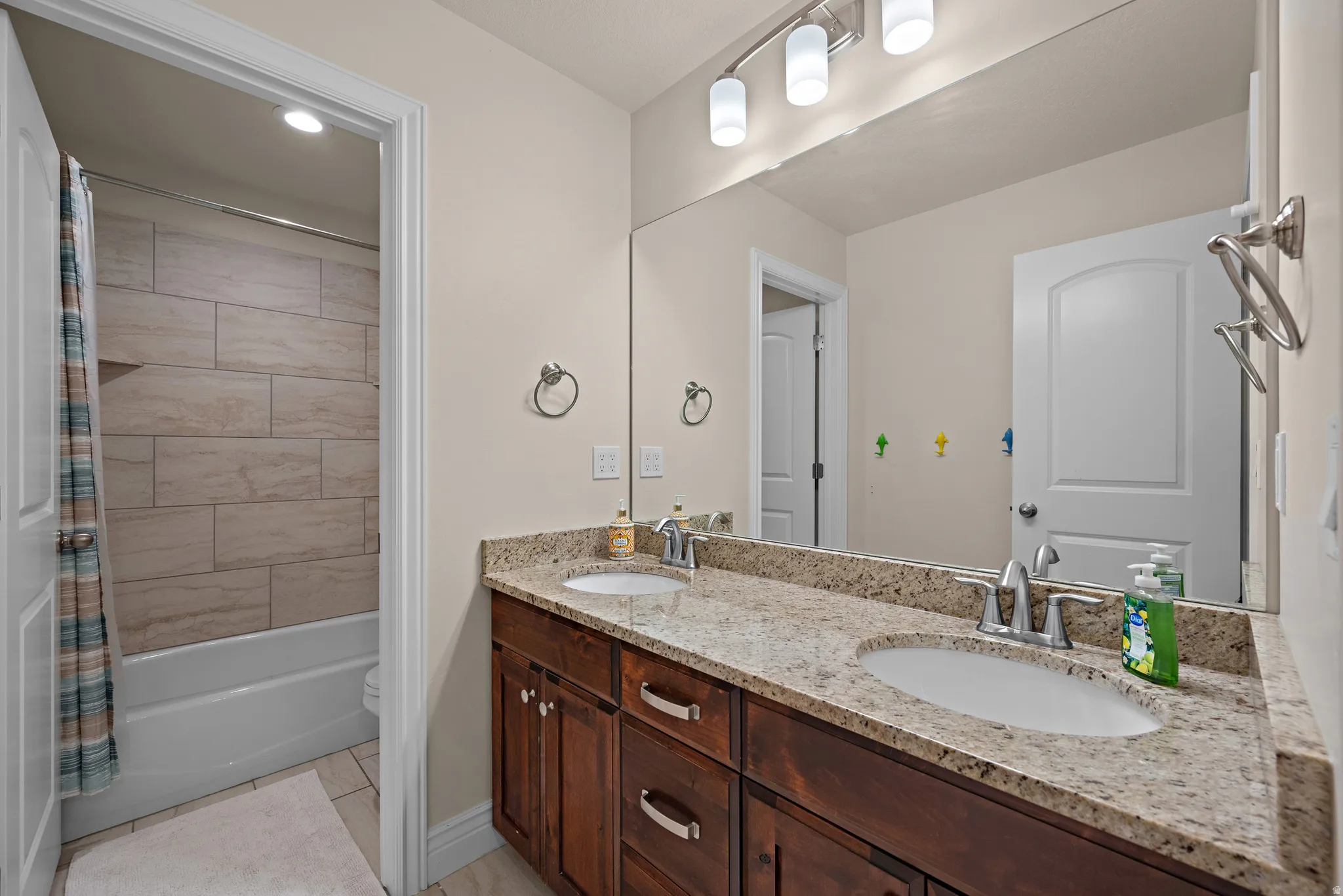 Dual vanity with stone-finish countertop, undermount sinks, and wood-finish cabinetry