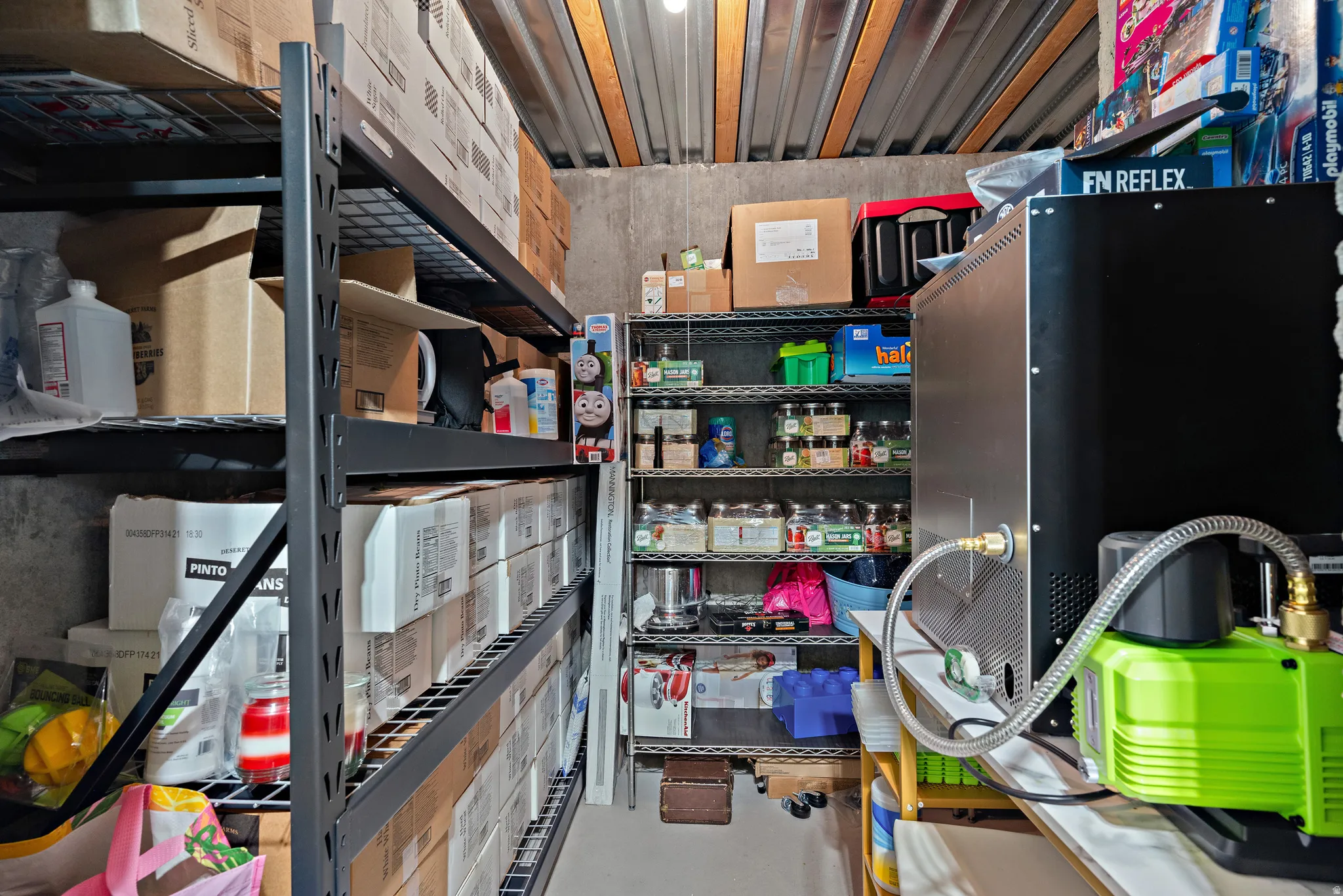 Utility room featuring industrial-style shelving, corrugated metal ceiling, and concrete walls