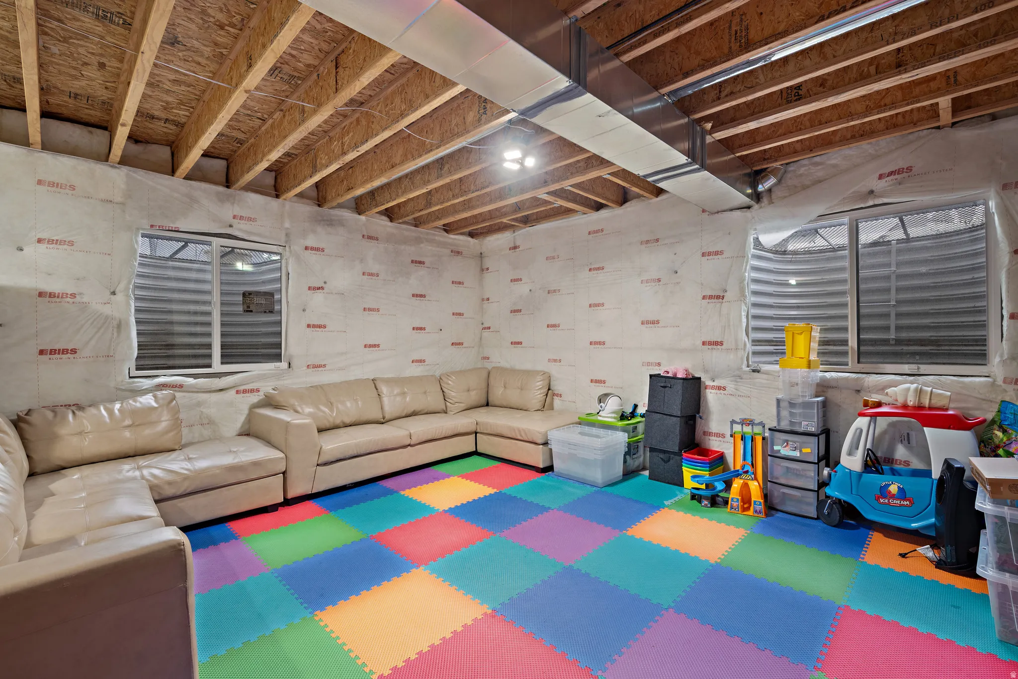 Unfinished basement space with exposed ceiling joists, multiple egress windows, and visible ductwork