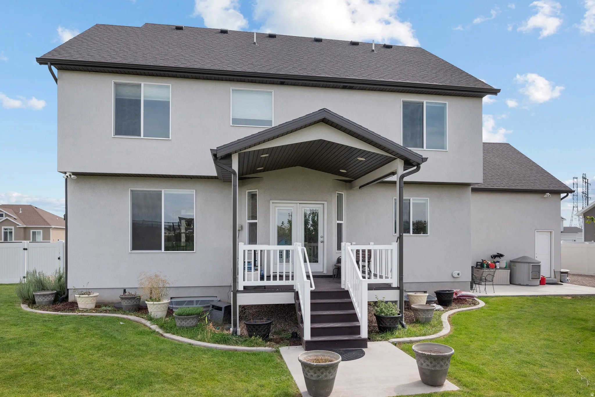 Two-story stucco exterior with a covered patio and deck