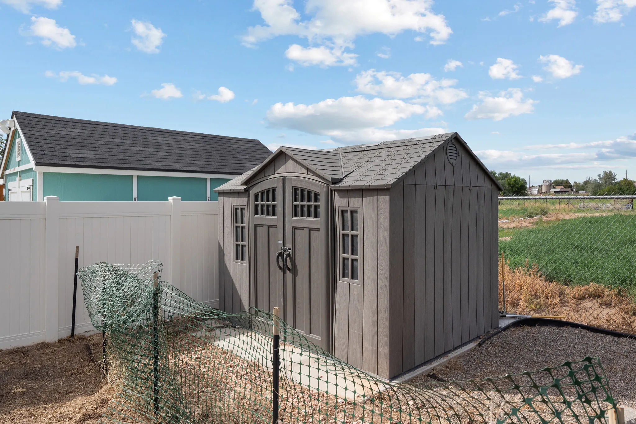 Private vinyl fencing, gravel pathway, and a durable storage shed with gable roof
