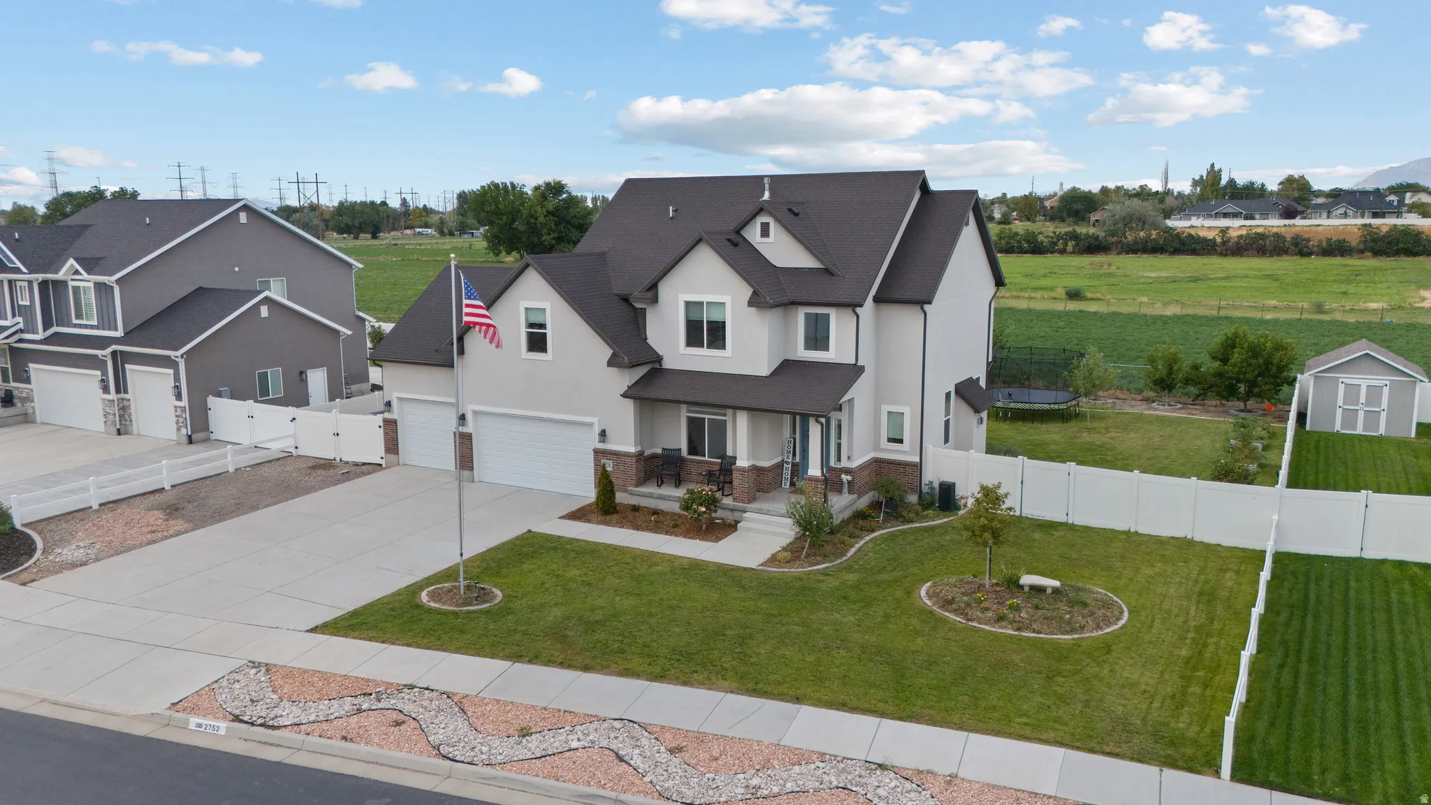 Two-story residence featuring a two-car garage, covered front porch, and a fenced backyard with a storage shed