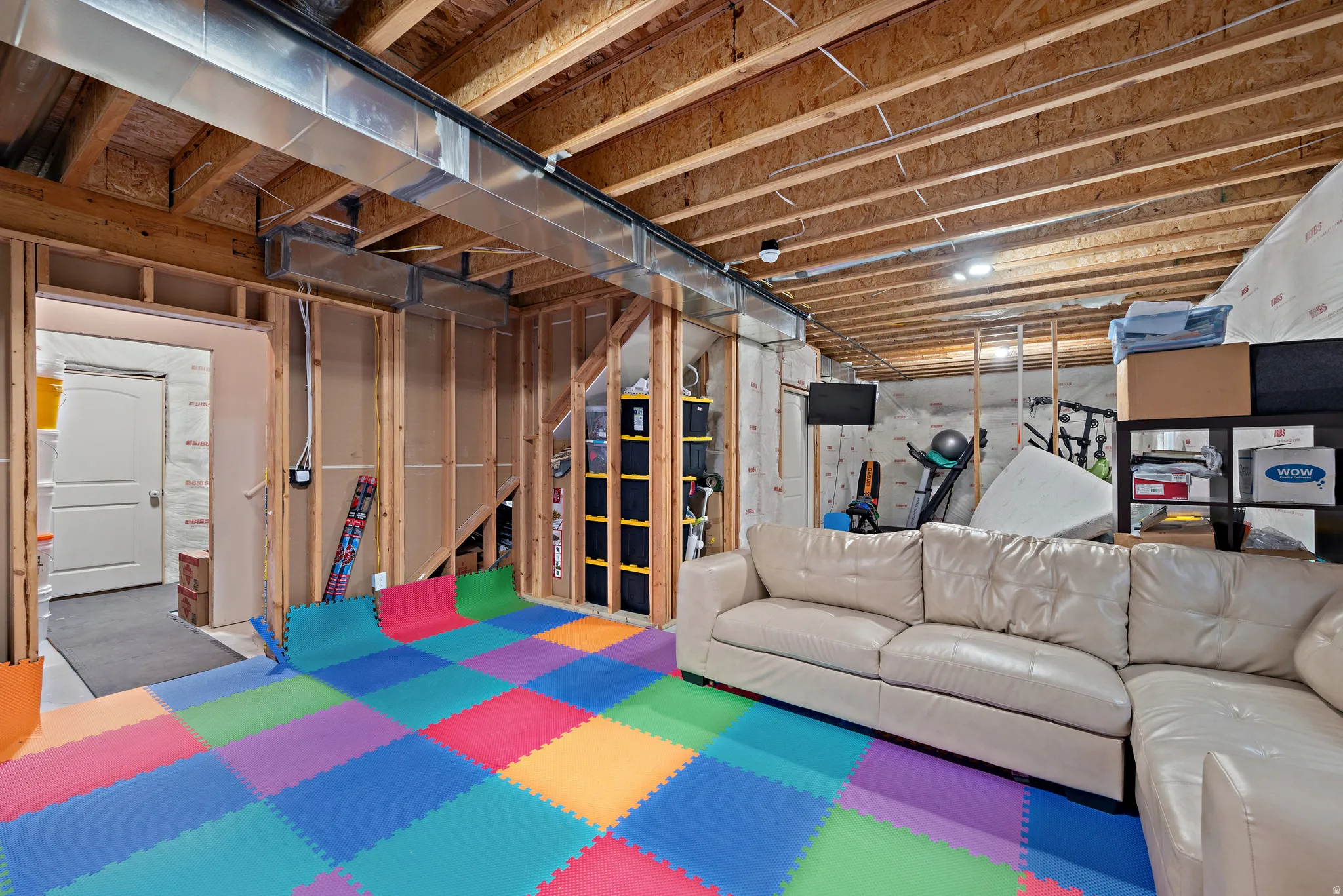Unfinished basement with exposed wood joists, framed walls, and visible ductwork