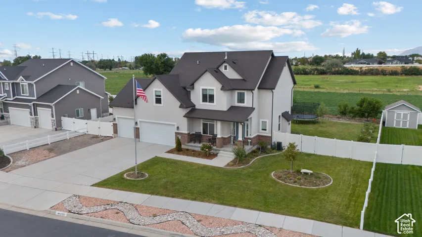 Two-story residence featuring a two-car garage, covered front porch, and a fenced backyard with a storage shed