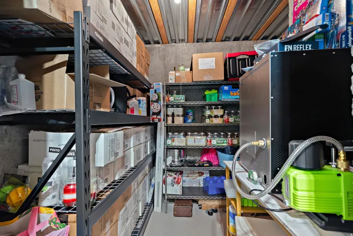 Utility room featuring industrial-style shelving, corrugated metal ceiling, and concrete walls