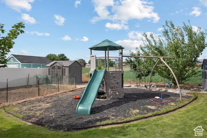 Expansive backyard featuring a fenced garden area, a storage shed, and a dedicated play area with a swing set and slide structure