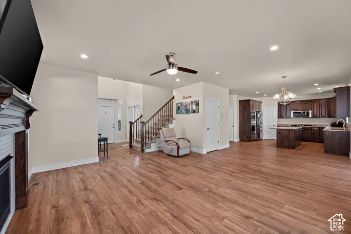 Spacious living area featuring wood-finish flooring, a fireplace with a white tile surround, and a ceiling fan