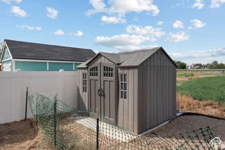 Private vinyl fencing, gravel pathway, and a durable storage shed with gable roof