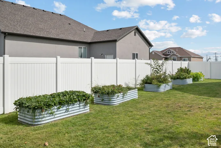 Private backyard featuring a white vinyl fence, established lawn, and multiple corrugated metal planter boxes