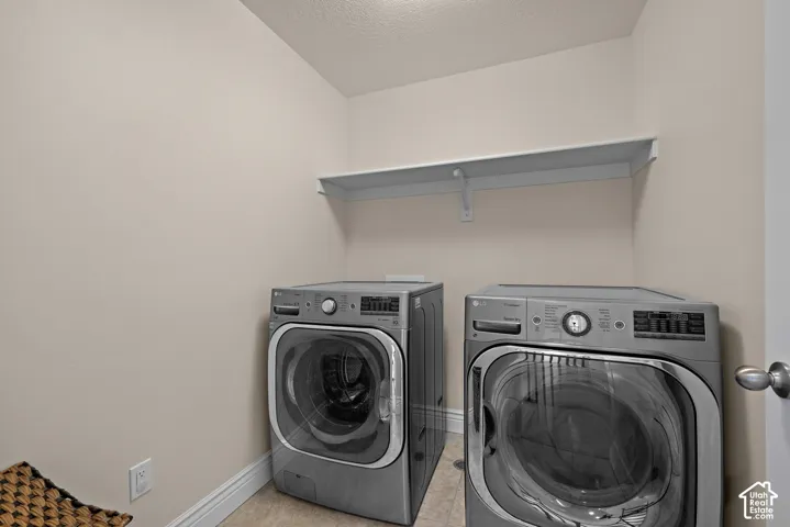 Laundry area with neutral wall tones, tile flooring, and a built-in wall shelf