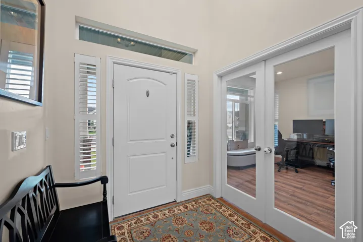 Entryway with a white paneled door, transom window, and sidelights with plantation shutters