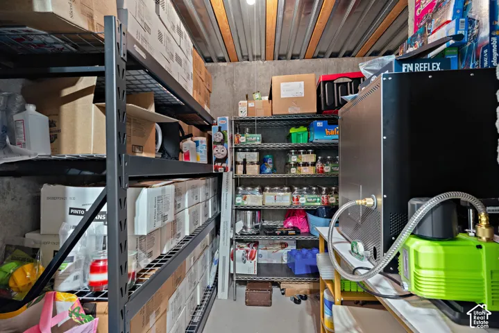 Utility room featuring industrial-style shelving, corrugated metal ceiling, and concrete walls
