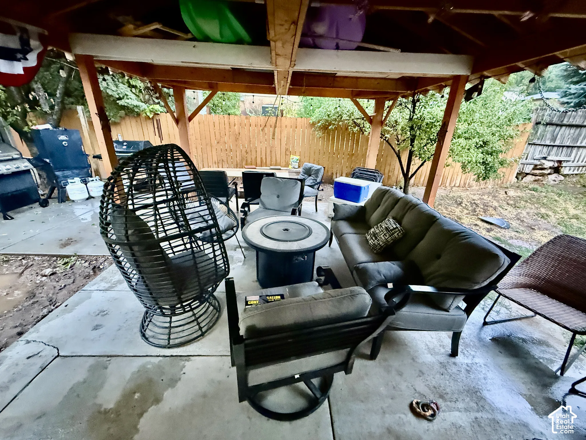 Covered patio with a wood frame structure, concrete flooring, and a wood privacy fence