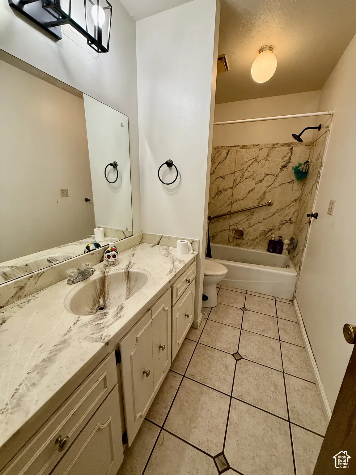 Bathroom with a single vanity, a built-in bathtub, and patterned floor tiling