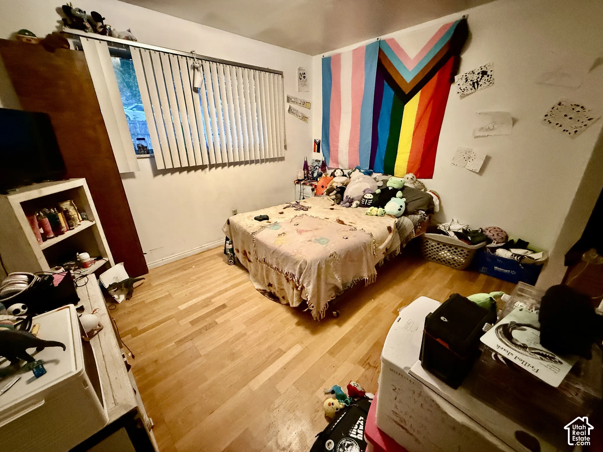 Wood-finish flooring with white baseboards and a window with blinds