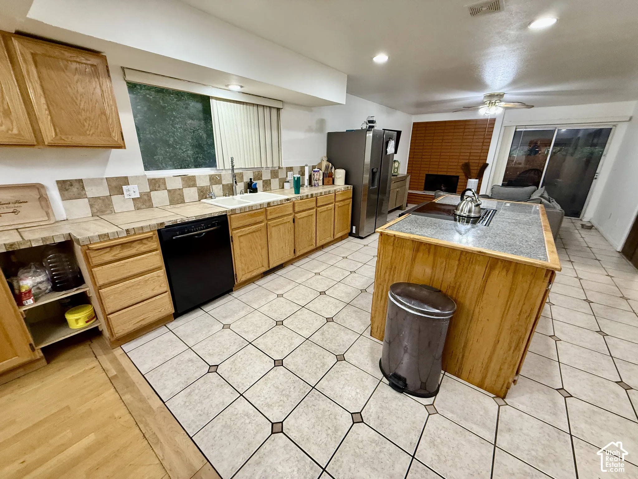 Kitchen featuring wood cabinetry, a built-in dishwasher, tile countertops, a tile backsplash, and a center island with a built-in cooktop