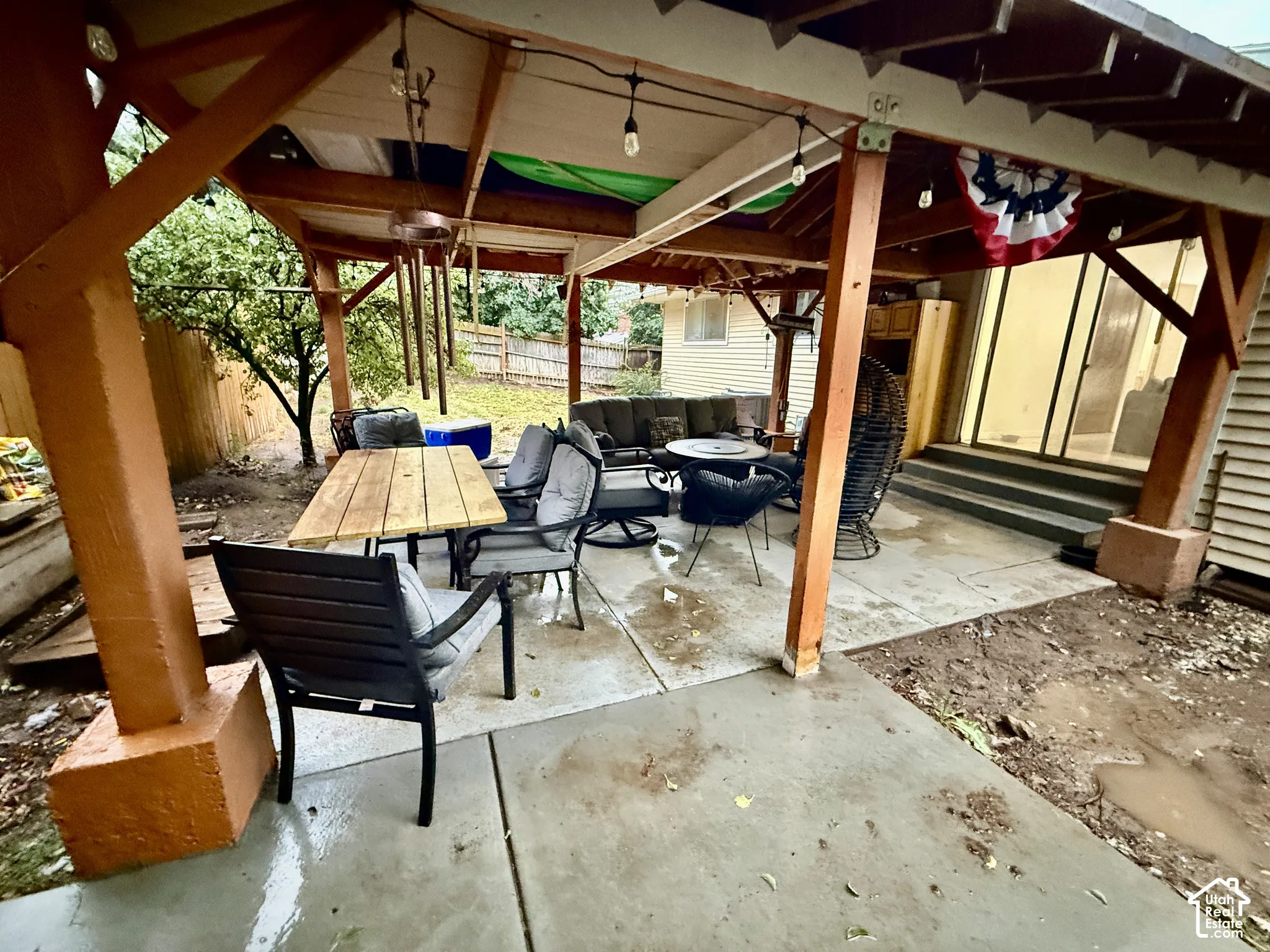 Covered patio structure with exposed wood beams and concrete flooring