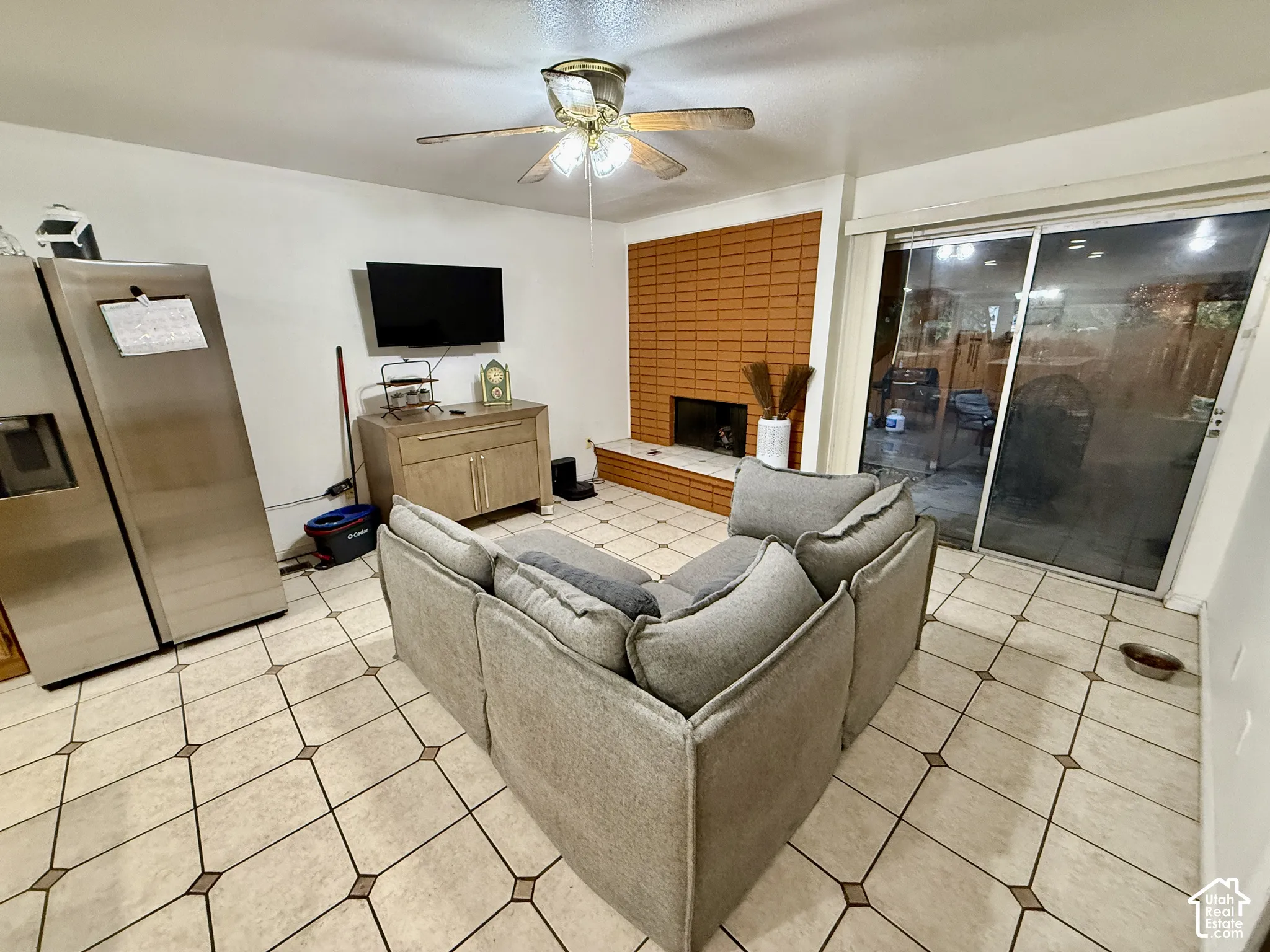Tiled flooring with accent squares, brick-faced fireplace with hearth, and sliding glass doors
