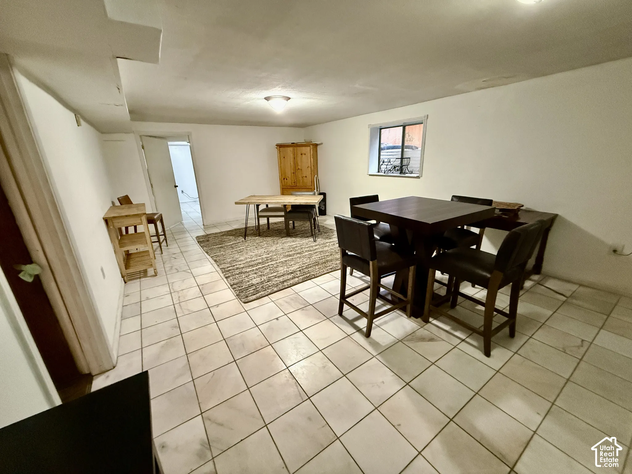 White tile flooring extending throughout the space, recessed lighting, and a window providing natural light